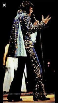 elvis presley performing on stage with his hands in the air