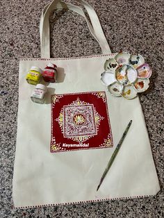 a tote bag sitting on top of a table next to paintbrushes and paints