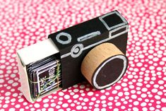 a camera made out of cardboard sitting on top of a pink and white tablecloth