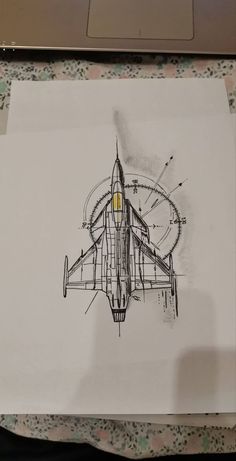 a drawing of a plane on paper with a laptop in the background