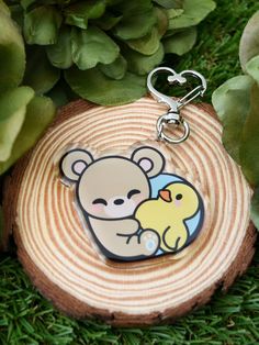 a keychain with a bear and duck on it sitting next to some plants