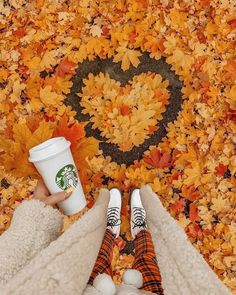 two people standing in front of a rug with leaves on it and one holding a starbucks cup