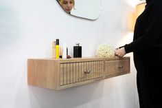 a woman standing in front of a wooden shelf with cosmetics and perfumes on it