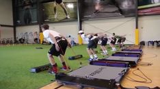 a group of men standing on top of treadmills in a gym with green grass