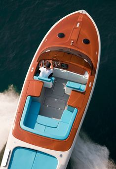 an orange and blue boat is in the water with two people on it's back