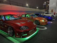 several cars parked in a parking lot with lights on the front and side of them