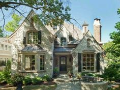 a large brick house with lots of windows and landscaping around the front door is surrounded by greenery