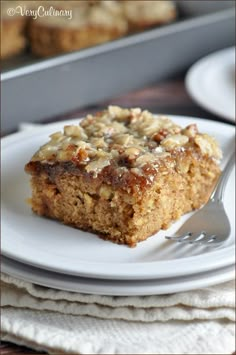 a piece of cake sitting on top of a white plate next to a pan of muffins