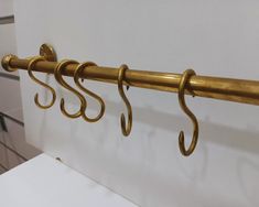 three brass hooks hang on the side of a white wall