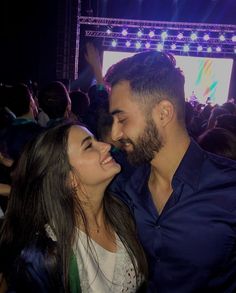 a man and woman standing next to each other in front of a crowd at a concert