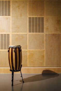 a large wooden drum sitting on top of a metal stand in front of a wall