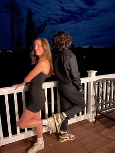 two people standing on a deck at night with the moon in the sky behind them