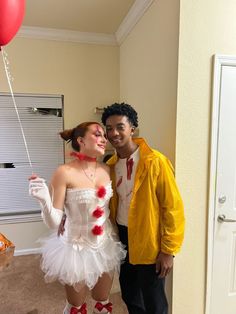 a man and woman dressed up as clowns pose for a photo in front of a balloon