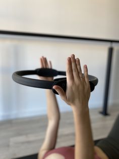 a woman laying on the floor with her hands in the air while holding onto a black object