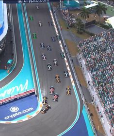 a group of motorcyclists driving down a race track in front of a crowd