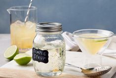 two glasses filled with lemonade and limeade sitting on a cutting board next to each other