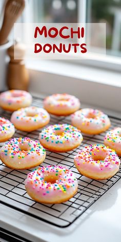 doughnuts with sprinkles are cooling on a rack in front of a window