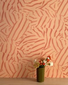 a vase filled with flowers sitting on top of a wooden table next to a wall