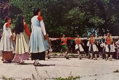 several people dressed in traditional clothing are dancing on the street with trees in the background