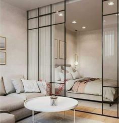 a living room filled with furniture and a large glass wall separating it from the bedroom