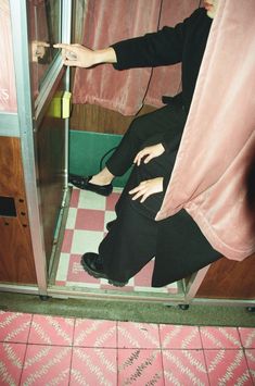 a woman sitting on the floor in front of a glass door with her legs crossed