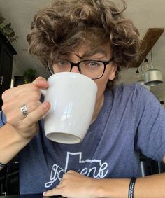 a person wearing glasses drinking from a coffee cup