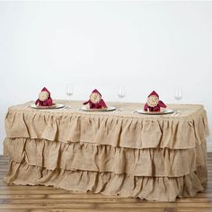 a table topped with three plates covered in burlap and red napkins next to wine glasses