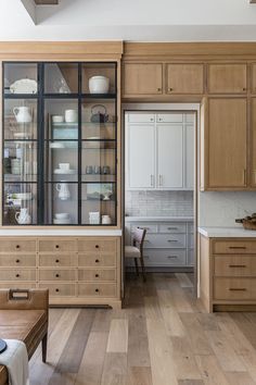 a kitchen with wooden cabinets and white dishes on the counter top, along with a dining room table