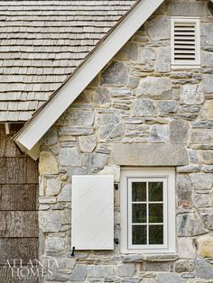 an old stone house with white shutters and windows