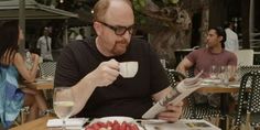 a man sitting at a table drinking from a cup