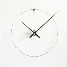 a clock that is on the side of a white wall with black hands and numbers