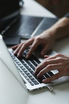 a person typing on a laptop computer at a desk with their hands resting on the keyboard