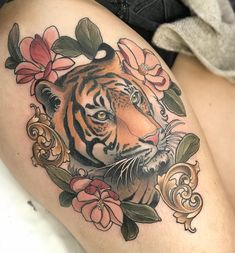 a close up of a tattoo on a woman's thigh with flowers and a tiger