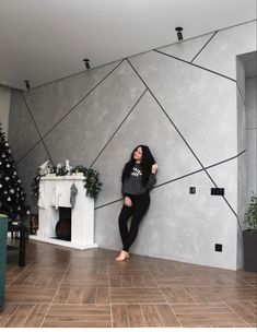 a woman leaning against a wall in front of a christmas tree