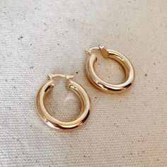 Featuring hypoallergenic 18k gold-filled material, these beautiful 25mm classic tube hoop earrings are the perfect accessory for any modern woman. With a timeless design, these earrings will complete any outfit or make a perfect and luxurious gift. Metal: 18k Gold Filled 25mm diameter x 5 mm thick hollow tube Latch closure Weight: 5.5 grams / pair Hypoallergenic + Waterproof Handcrafted in Brazil Expensive Brands, Tube Hoop Earrings, Wholesale Jewelry Supplies, Satin Set, Gold Filled Hoops, Pendant Rings, Beauty Items, Made In Brazil, Water Proof