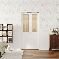 a living room with white walls and wooden flooring next to a brown chest of drawers