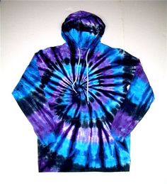 a blue and purple tie - dyed hoodie is hanging on the wall in front of a white wall