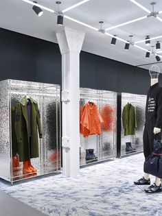 mannequins dressed in black and orange are lined up against the glass walls