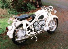 a white motorcycle parked on the side of a road next to some trees and grass