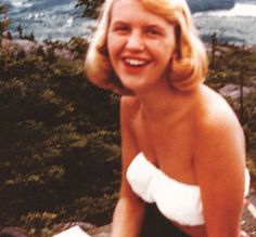 a woman sitting on top of a rock next to the ocean