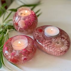 three pink glass candles are sitting on a table