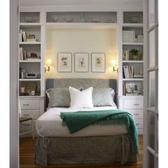 a bed sitting inside of a bedroom next to a white book shelf filled with books