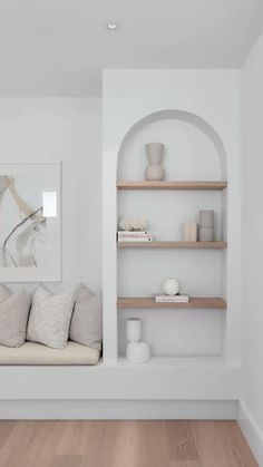 a living room with white walls and shelves filled with vases on top of them