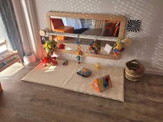 a child's play room with toys on the floor and in front of a mirror