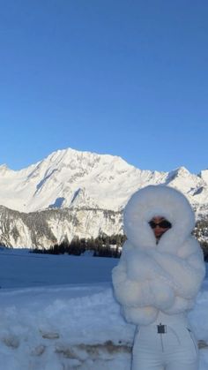 a person standing in the snow with their arms around each other and mountains in the background