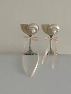 two silver candlesticks with bows on them