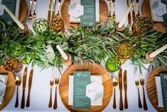 the table is set with pineapples, greenery and place settings for dinner