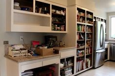 a kitchen with white cabinets and shelves filled with food