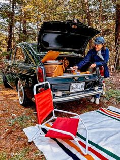 a man sitting in the back of a car next to a picnic blanket