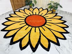 a large yellow and black flower rug on top of a white marble floor with potted plants in the background